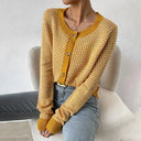 Person wearing a yellow patterned cardigan sitting on a white couch.