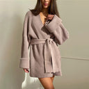 Woman wearing a pink ribbed knit cardigan against a plain background