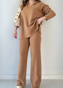 Person wearing a brown ribbed sweater and pants against a white background