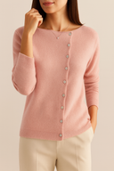Woman wearing a Pink cardigan against a beige background