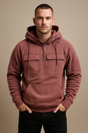 Man wearing a maroon hoodie with front pockets on a beige background