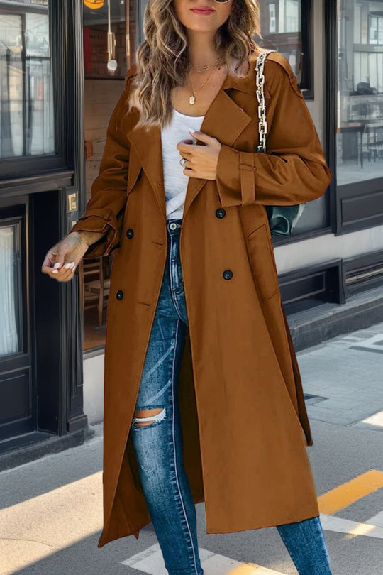 Woman wearing a brown trench coat and ripped jeans on a city street.
