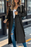 Woman wearing a black trench coat and ripped jeans on a city street.