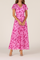 Woman wearing a pink floral dress on a plain background