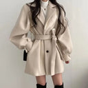 Beige trench coat worn by a person on a plain background