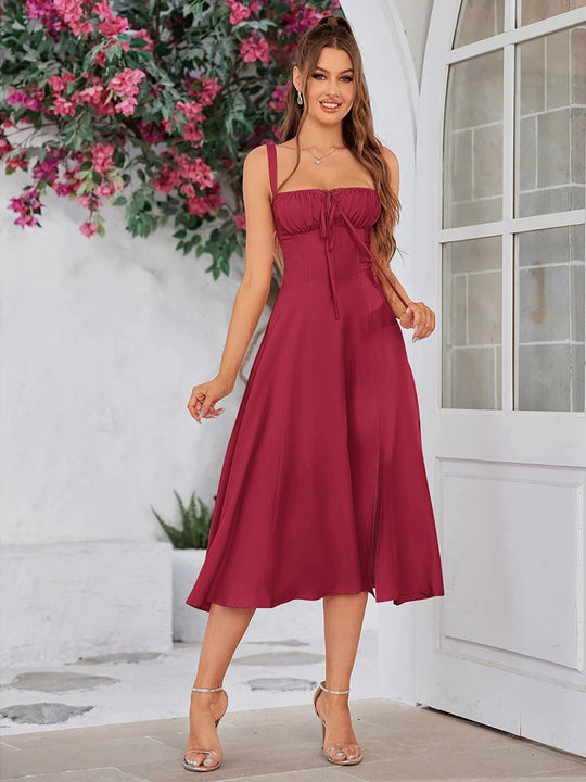 Woman in a red dress standing in front of a white door with floral decorations.