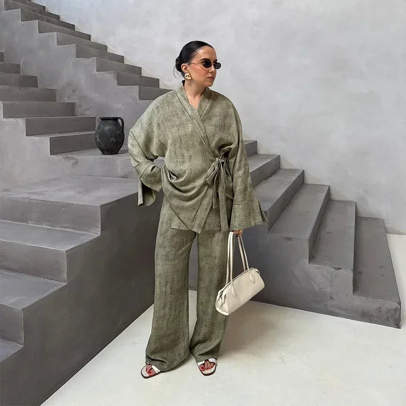 Woman in a green outfit standing on a staircase holding a white bag.
