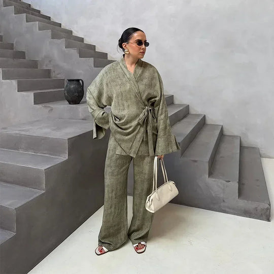 Woman in a green outfit standing on a staircase holding a white bag.
