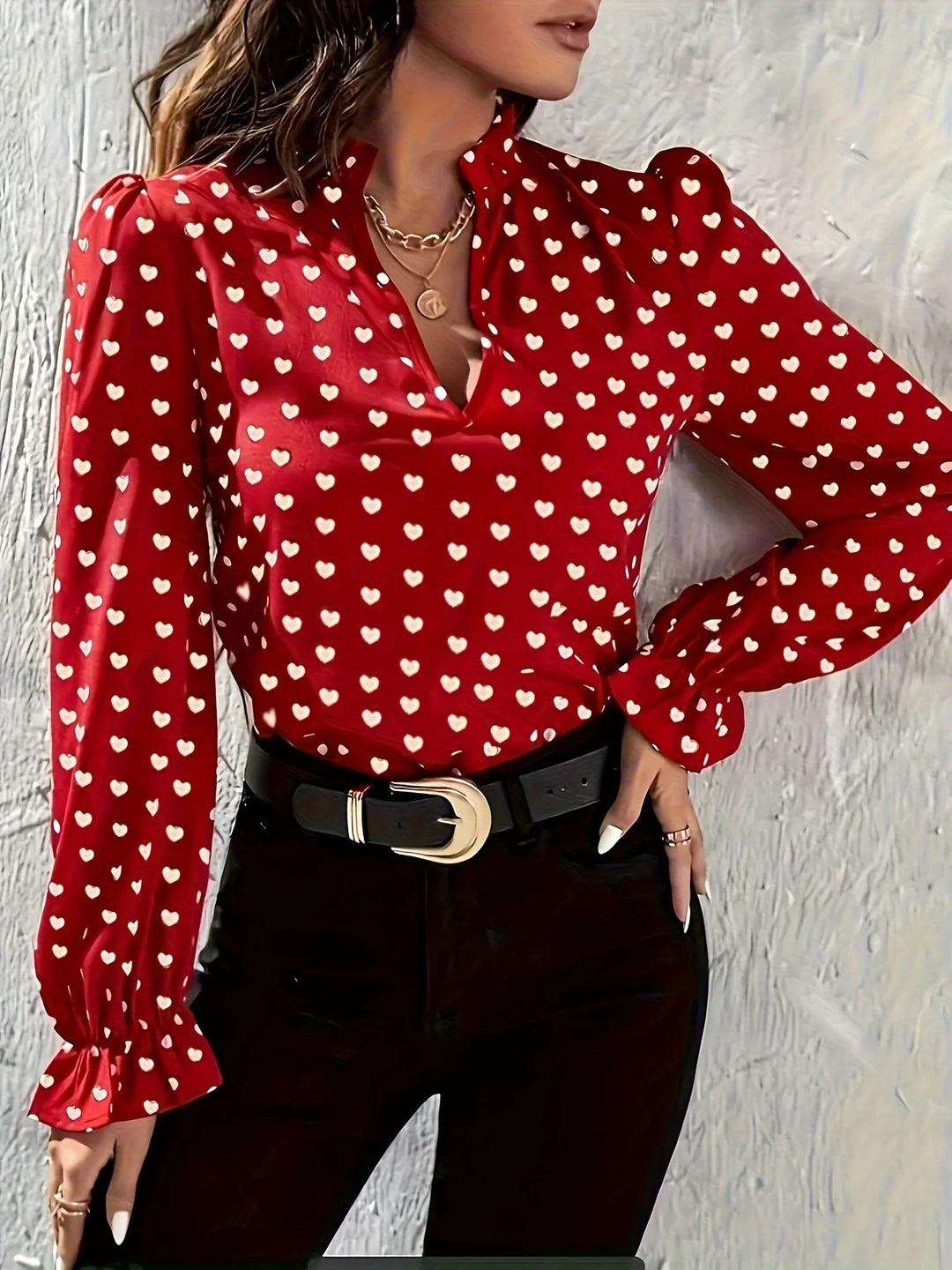 Red polka dot blouse with long sleeves worn by a person against a light gray background