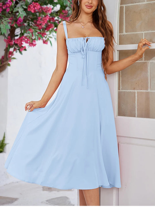 Woman wearing a light blue dress standing in front of a door with flowers in the background