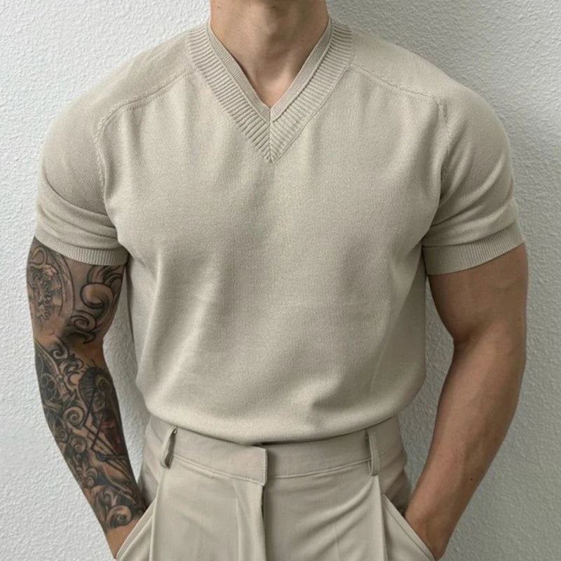 Man wearing a beige short-sleeve sweater and pants against a plain background