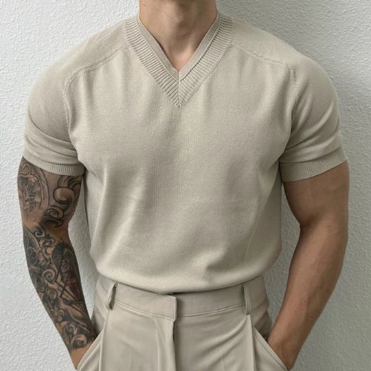 Man wearing a beige short-sleeve sweater and pants against a plain background