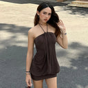 Woman wearing a brown halter neck dress standing outdoors on a sunny day.