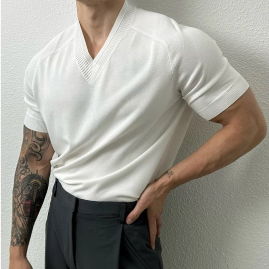 Person wearing a white short-sleeve sweater against a plain background