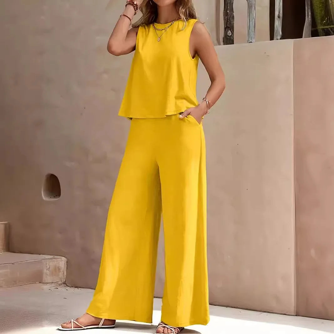 Woman wearing a yellow sleeveless top and wide-leg pants against a beige wall.