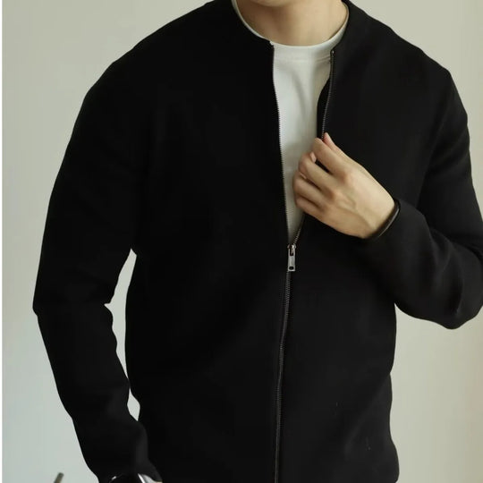 Person wearing a black jacket over a white shirt on a plain background