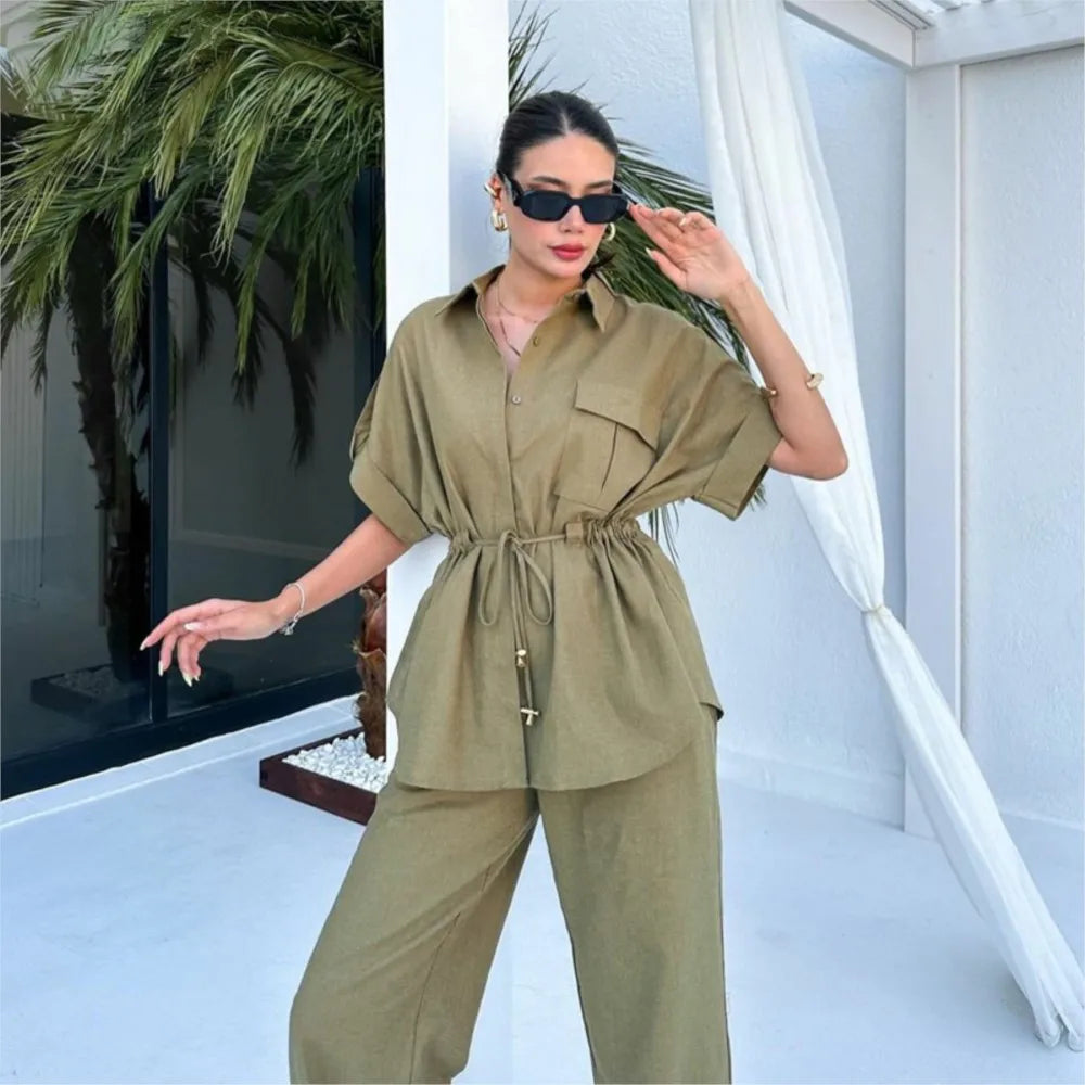 Woman in a green outfit standing in a modern indoor setting with plants.