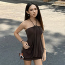 Woman in a brown dress holding a camera on a street