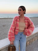 Woman wearing a pink sweater on a beach at sunset