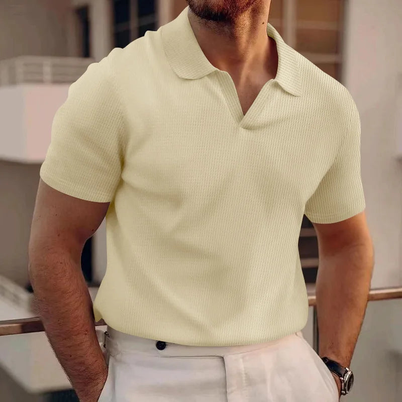Man wearing a light green polo shirt and white pants indoors.