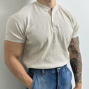 Person wearing a beige short-sleeve shirt and blue jeans against a plain background