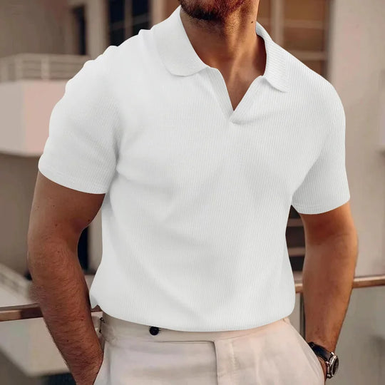 Man wearing a white polo shirt in an indoor setting