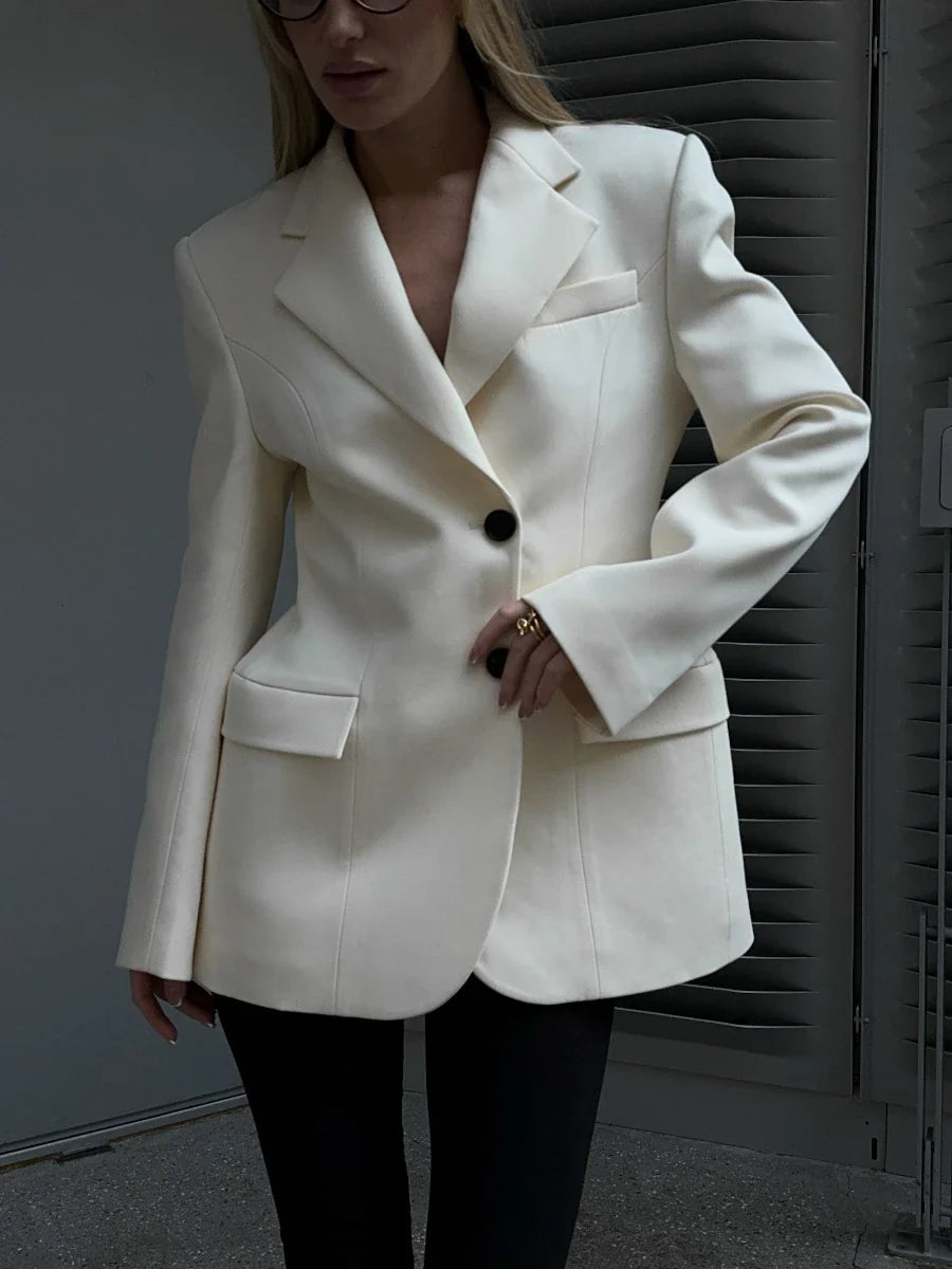 Person wearing a white blazer with a blurred background