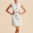 White dress with gold buttons on a beige background
