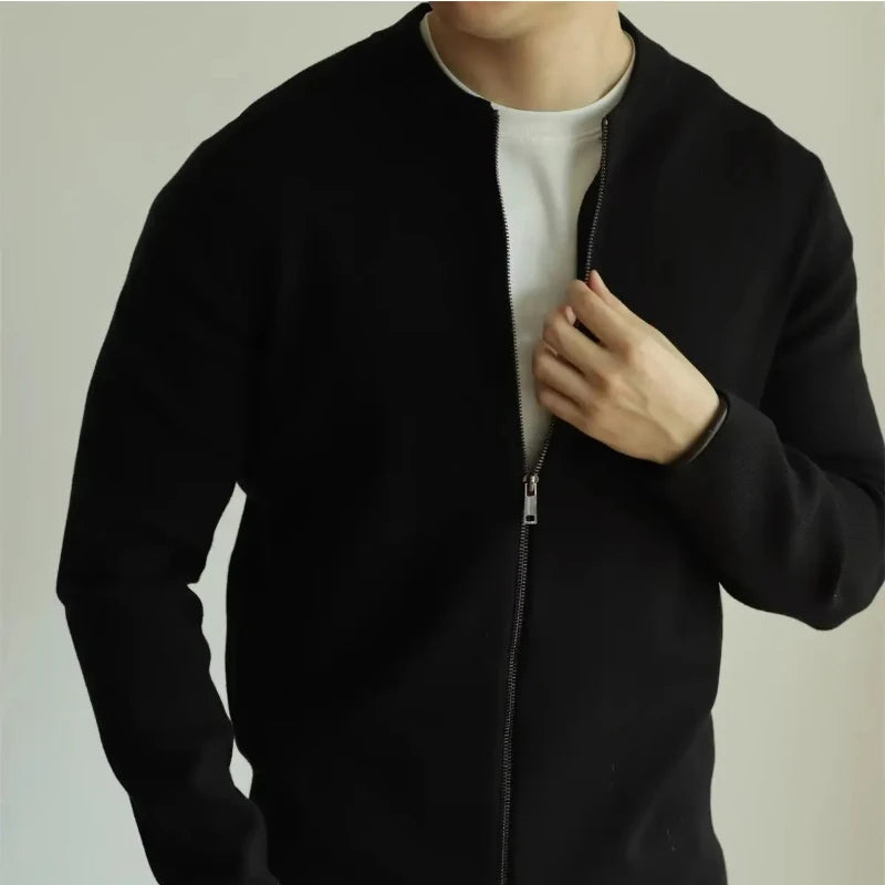 Person wearing a black jacket over a white shirt on a plain background
