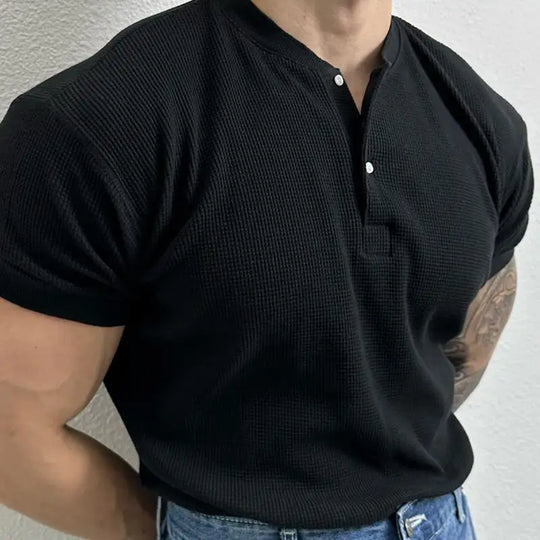 Person wearing a black short-sleeve shirt with a textured pattern on a plain background