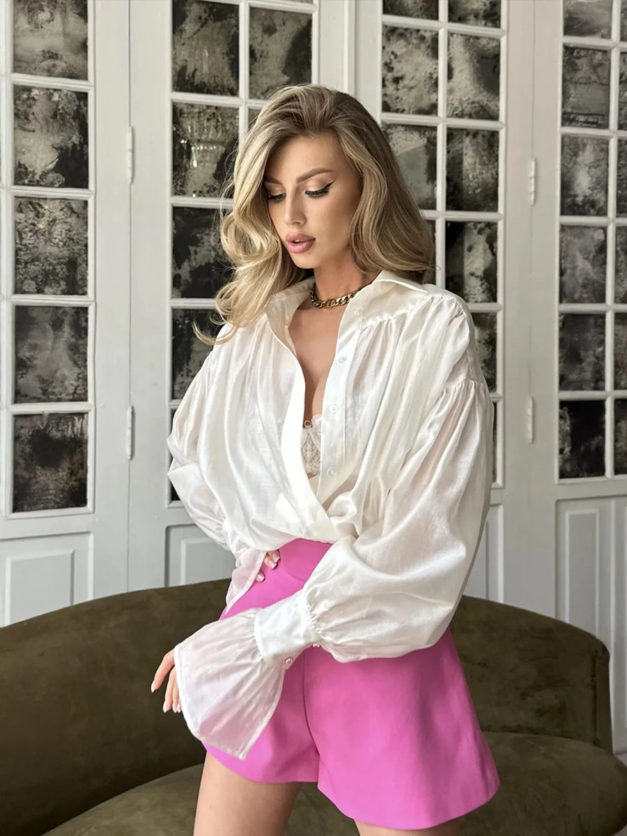Woman wearing a white blouse and pink shorts in a room with decorative glass doors.