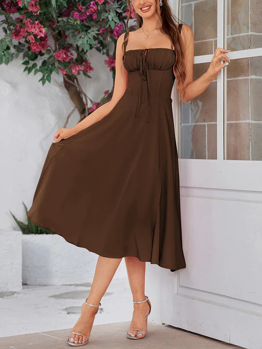 Woman wearing a brown dress standing in front of a white door with floral decorations.