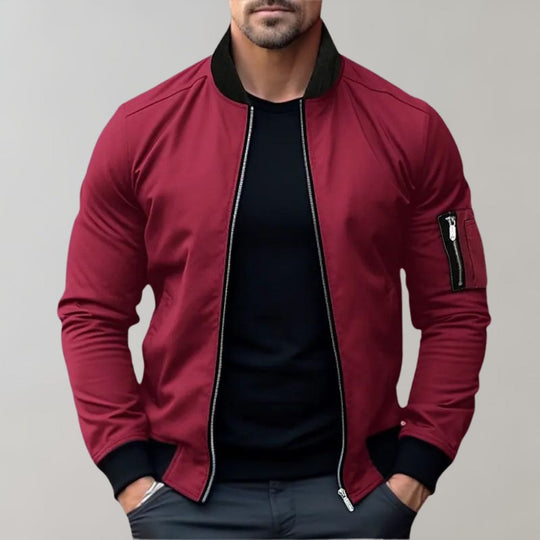 Red bomber jacket with black trim worn by a person on a gray background