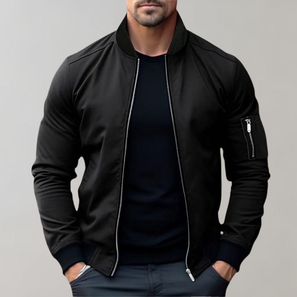 Man wearing a black bomber jacket against a gray background