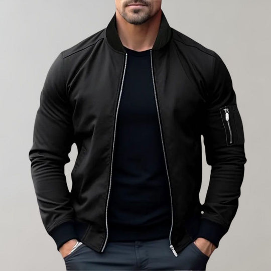 Man wearing a black bomber jacket against a gray background