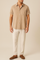 Man wearing a beige short-sleeve shirt and light-colored pants on a beige background