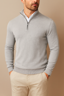 Man wearing a gray quarter-zip sweater and beige pants against a beige background