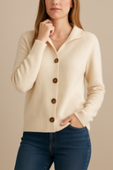 Woman wearing a beige cardigan with brown buttons on a beige background