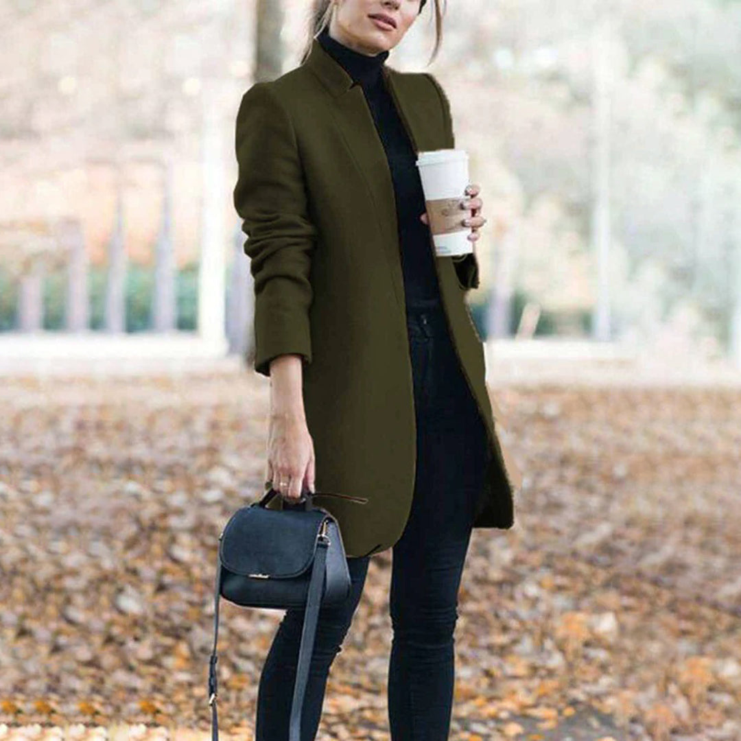 Woman wearing an olive green coat holding a coffee cup outdoors.
