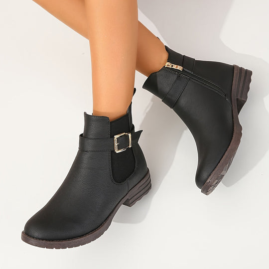 Black ankle boots with a buckle detail on a white background