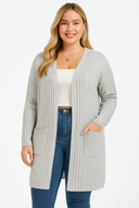 Woman wearing a light gray ribbed cardigan over a white top and blue jeans on a white background