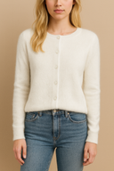 Woman wearing a white cardigan and blue jeans against a beige background