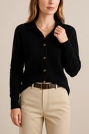Woman wearing a black cardigan and beige pants on a beige background