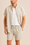 Man wearing a light-colored shirt and shorts set on a beige background