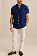 Man wearing a blue short-sleeve shirt and light-colored pants on a beige background