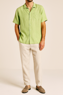 Man wearing a green shirt and beige pants on a plain background