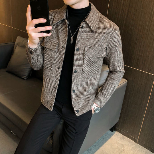 Person wearing a checkered jacket taking a mirror selfie in a room.