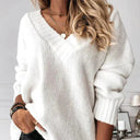 Person wearing a white sweater with a blurred background