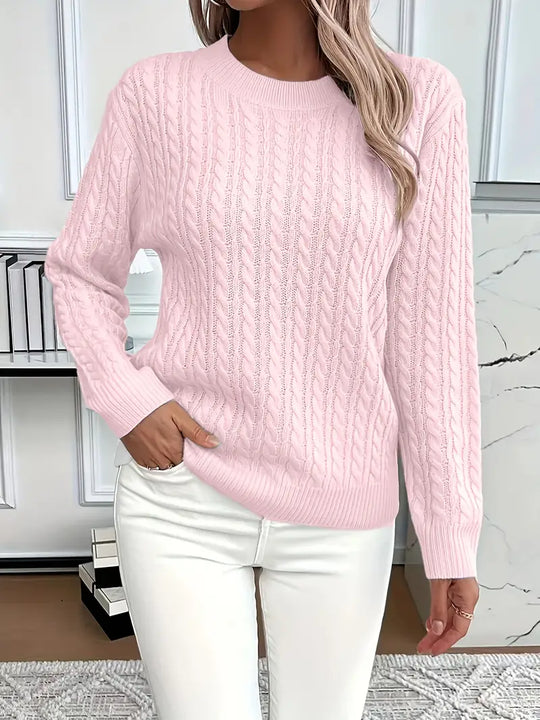 Person wearing a pink cable knit sweater and white pants in a room with a marble floor.