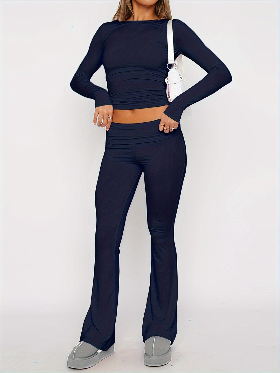 Person wearing a navy blue long-sleeve top and flared pants on a white background